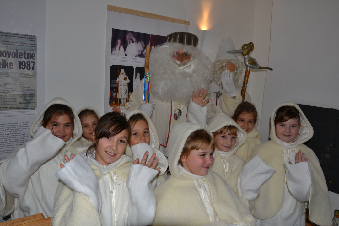 Siva kučma, bela brada, topel kožuh, zvrhan koš ...